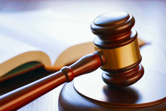 Gavel resting on sounding block beside open book.