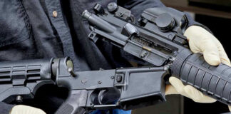 Person assembling a black rifle with gloves on.