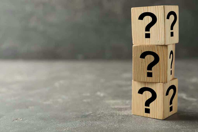 Three wooden blocks with black question marks stacked.