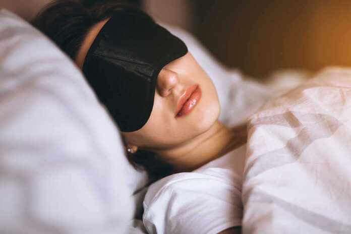 A woman wearing a sleep mask, resting in bed