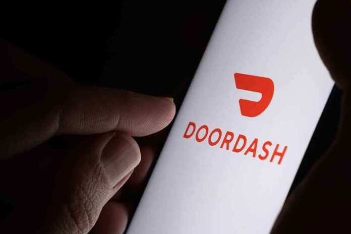 shutterstock_1637408869.jpg A hand holding a smartphone displaying the Doordash logo
