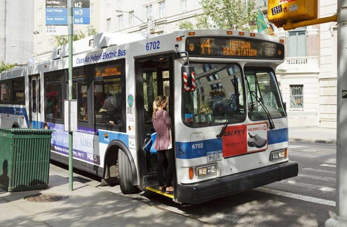A woman boarding a clean air hybrid electric bus at a city stop