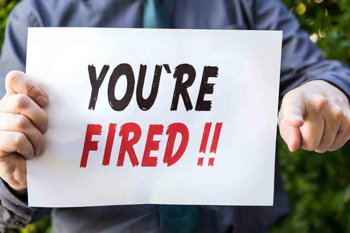 Person holding YOURE FIRED sign.