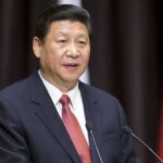 Xi UNLEASHES Digital Crackdown — Terrifying New Controls A political leader delivering a speech at a podium with national flags in the background