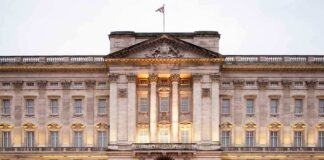 Front view of Buckingham Palace with illuminated facade and British flag
