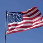 Clooney’s Citizenship Twist — What’s He Escaping? Waving American flag against a clear blue sky