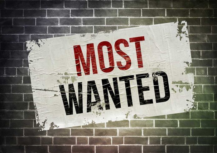 A weathered poster displaying the words MOST WANTED on a brick wall