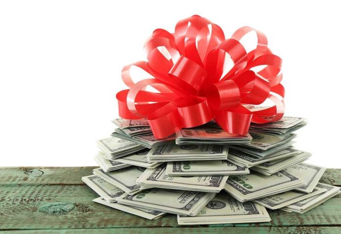 A stack of cash topped with a red ribbon bow