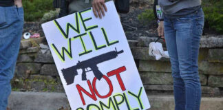Protest sign reads: We Will Not Comply.
