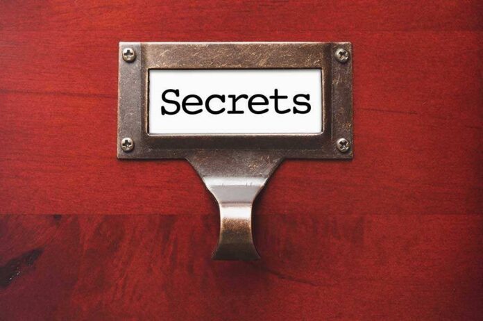 A label holder on a wooden surface with the word Secrets displayed