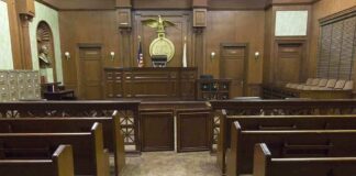 Interior view of an empty courtroom with wooden benches and a judges bench