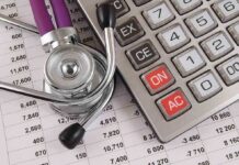 A stethoscope resting on a calculator and financial data sheets
