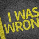 Bold yellow text on a dark asphalt surface stating I WAS WRONG