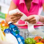 Trump Bets 2026 On Grocery Pain Person examining a receipt while shopping for groceries