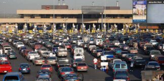 A crowded parking lot filled with cars near a border crossing
