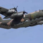 Military C-130 Hercules aircraft flying against a blue sky