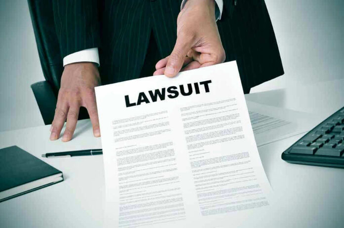 Person holding a document titled LAWSUIT in office.
