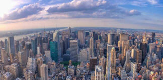 Aerial view of city with skyscrapers and cloudy sky.