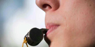 Person holding a whistle in their mouth.