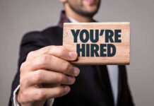 Person holding a Youre Hired sign.