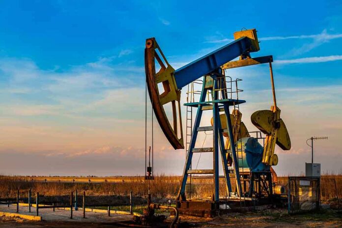 An oil pump jack operating against a sunset backdrop