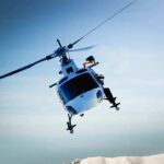 Rescue Chopper VANISHES Mid-Mission A helicopter flying over a mountainous landscape under a blue sky