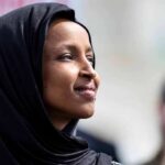 Woman wearing a black hijab looking thoughtfully during an outdoor event