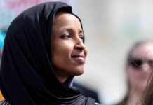 Woman wearing a black hijab looking thoughtfully during an outdoor event