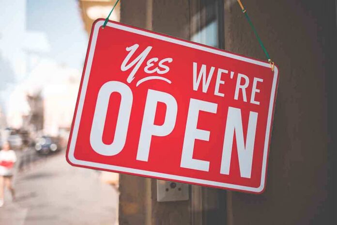 A red sign that reads Yes, We're Open hanging on a door