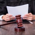 A judge holding documents with a gavel in the foreground