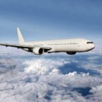 A white airplane flying above fluffy clouds in a blue sky