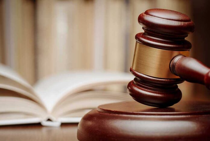 A wooden gavel resting on a sound block with law books in the background