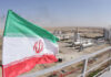 Iranian flag near an industrial gas refinery.