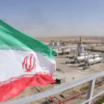 Iran’s Bluff Called—Allies Abandon Ship Iranian flag near an industrial gas refinery.