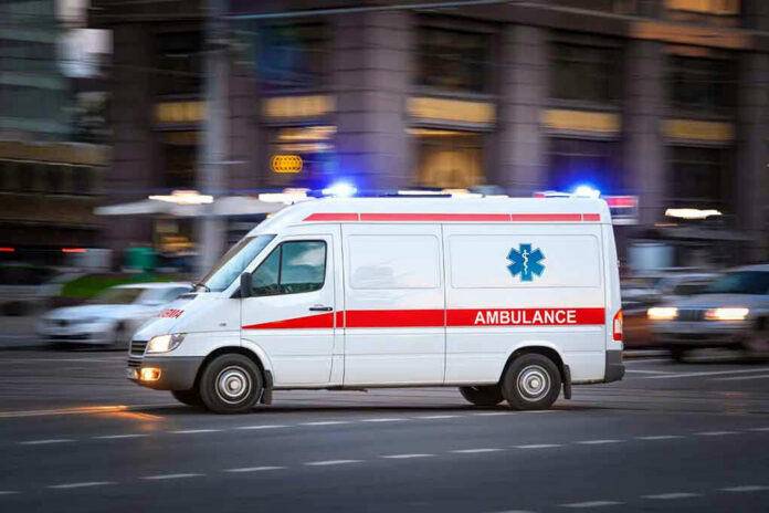 Ambulance driving on urban street with lights flashing.