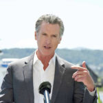 Hannity Savages Newsom On Podcast Debut Man speaking with microphone outdoors.
