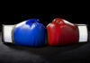 Blue and red boxing gloves facing each other.