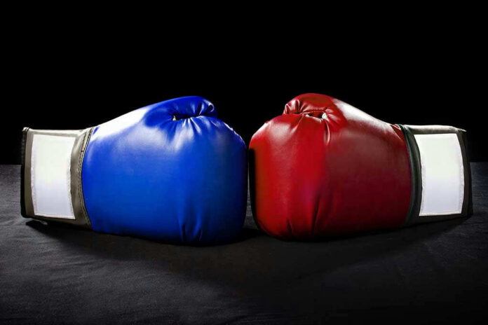 Blue and red boxing gloves facing each other.