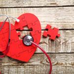 Heartbeat Ban Signed—Felonies Loom Red heart puzzle with stethoscope on wooden background.