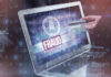 $17M FRAUD Ring—Foreign Nationals Stole Grandma’s Home Person holding credit card near laptop displaying Fraud.