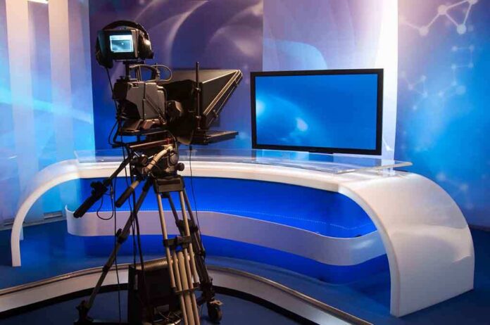 Television studio setup with a camera and monitor on a modern desk