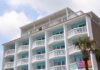 Exterior view of a beachfront hotel with balconies and colorful towels hanging