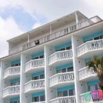 Exterior view of a beachfront hotel with balconies and colorful towels hanging