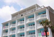 Exterior view of a beachfront hotel with balconies and colorful towels hanging