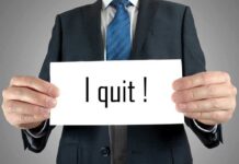 A man in a suit holding a sign that says I quit