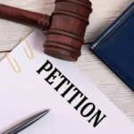 A gavel resting on a legal petition document with a pen and a folder