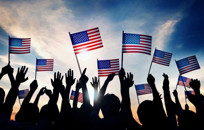 shutterstock_226614211.jpg Silhouetted crowd holding American flags against a sunset sky