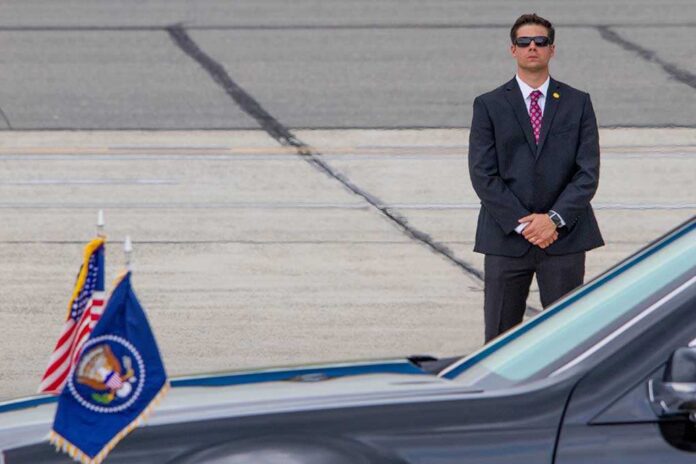 shutterstock_685967965 (2).jpg A security officer in a suit stands guard near a presidential vehicle at an airport