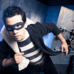 Thieves CRUSH Carlson’s Launch — SHOCKING DETAILS A masked thief in a striped shirt holding a bag while emerging from a bank vault
