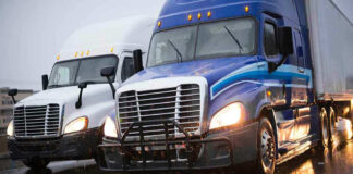 Two trucks driving on a wet road.